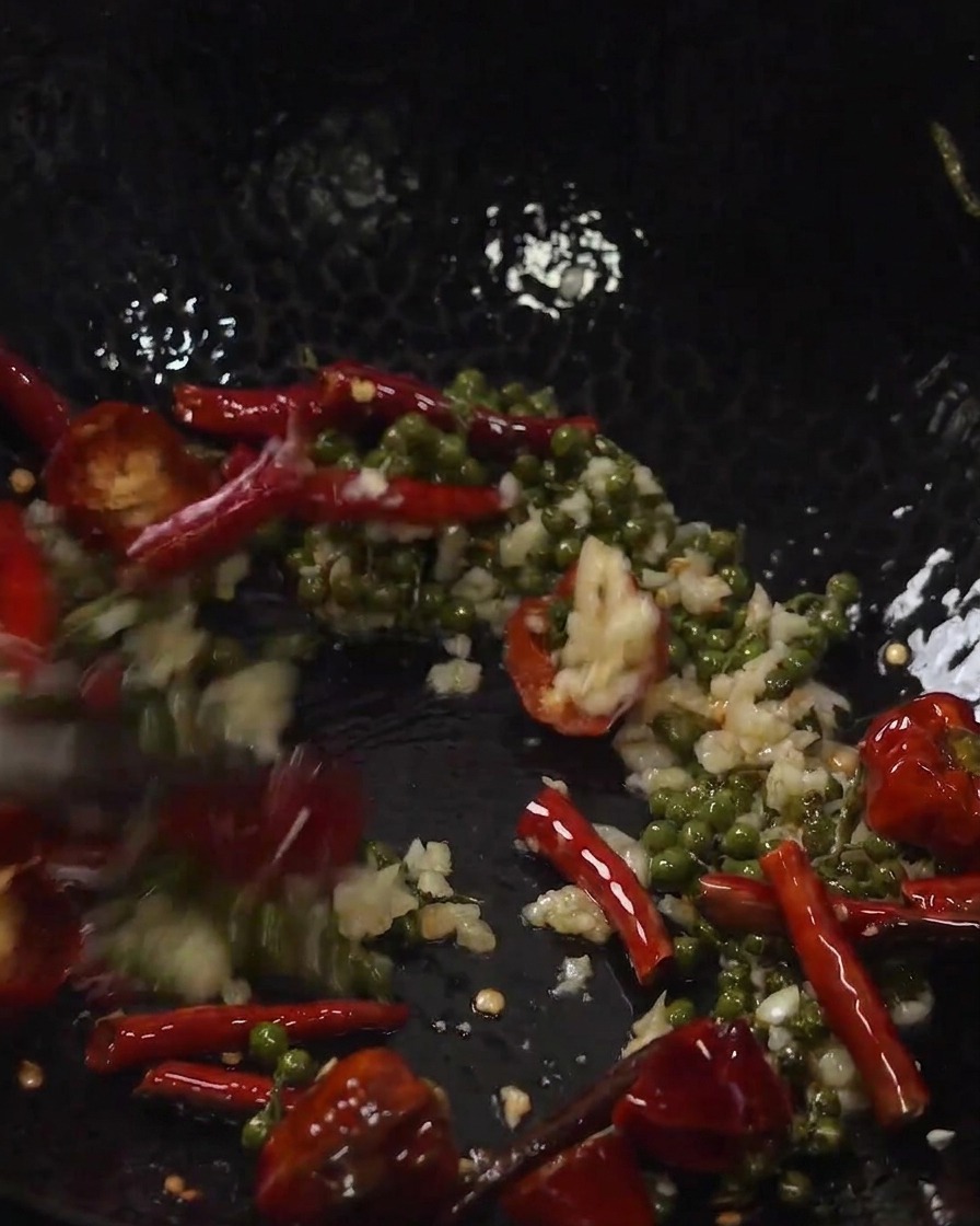Knusprig frittierte Schweinerippchen und Gewürze werden im Wok vermengt.