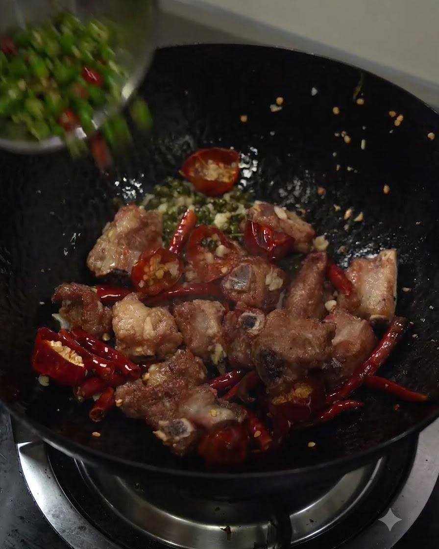 In Scheiben geschnittene grüne Chilischoten werden in den Wok gegeben.