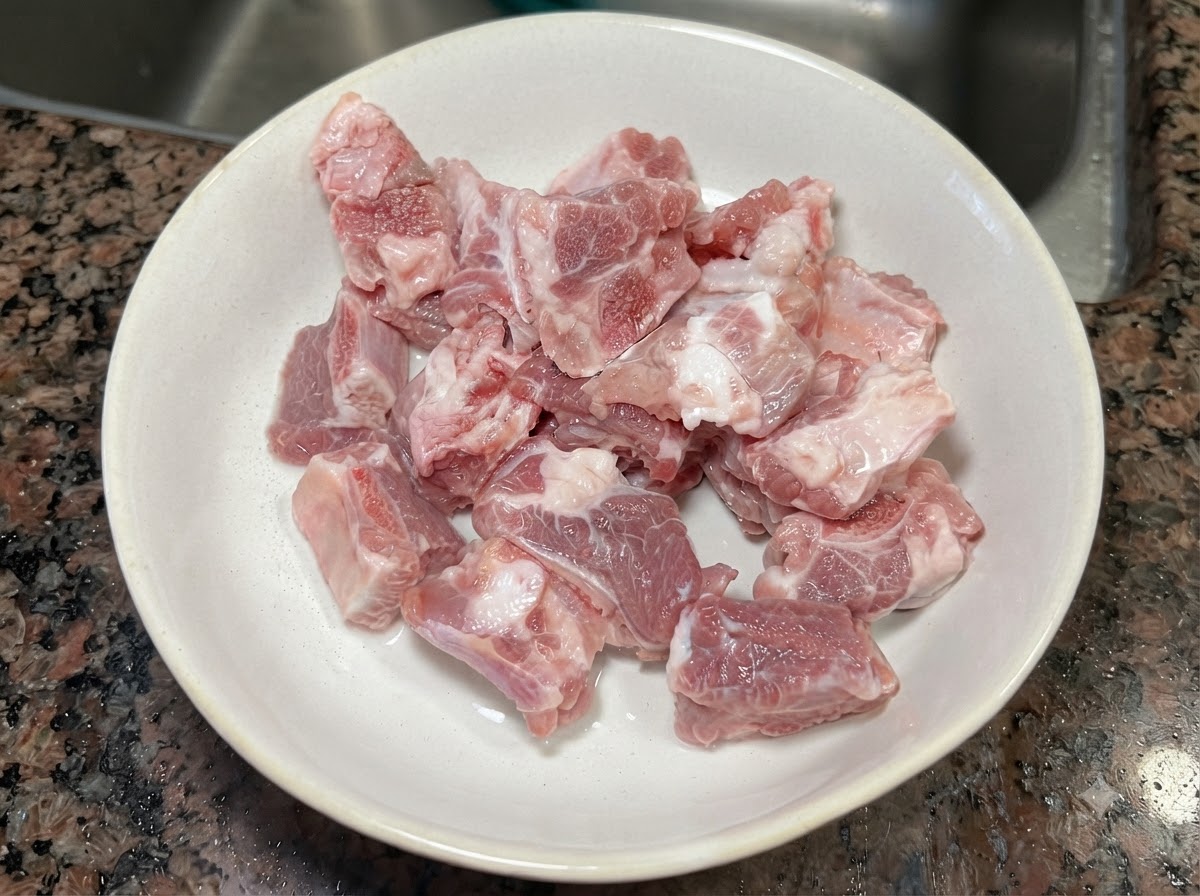 Frische rohe Schweinerippchenstücke in einer weißen Keramikschüssel.