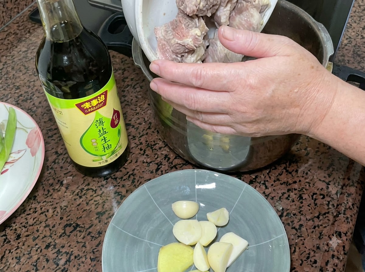Blanchierte Schweinerippchen werden in einen Schnellkochtopf gefüllt, neben einer Flasche heller Sojasauce und einem Teller mit Knoblauch und Ingwer.