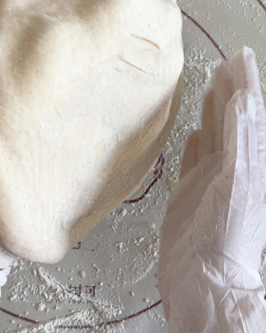 Flachgedrückter Pizzateig wird zwischen den Händen über einer bemehlten Matte hin und her geworfen.