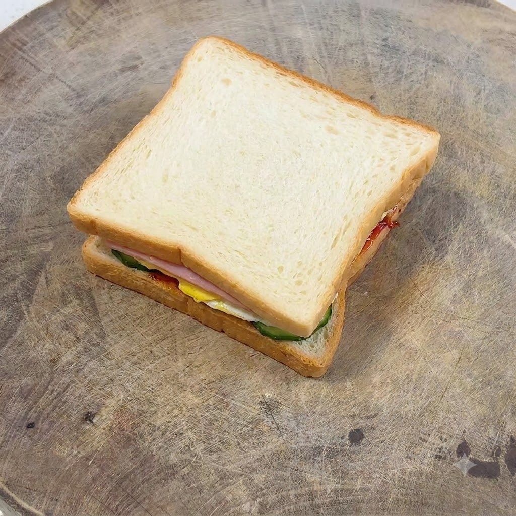 Eine Gabel verstreicht Mayonnaise gleichmäßig auf einer goldbraunen Scheibe Toastbrot.