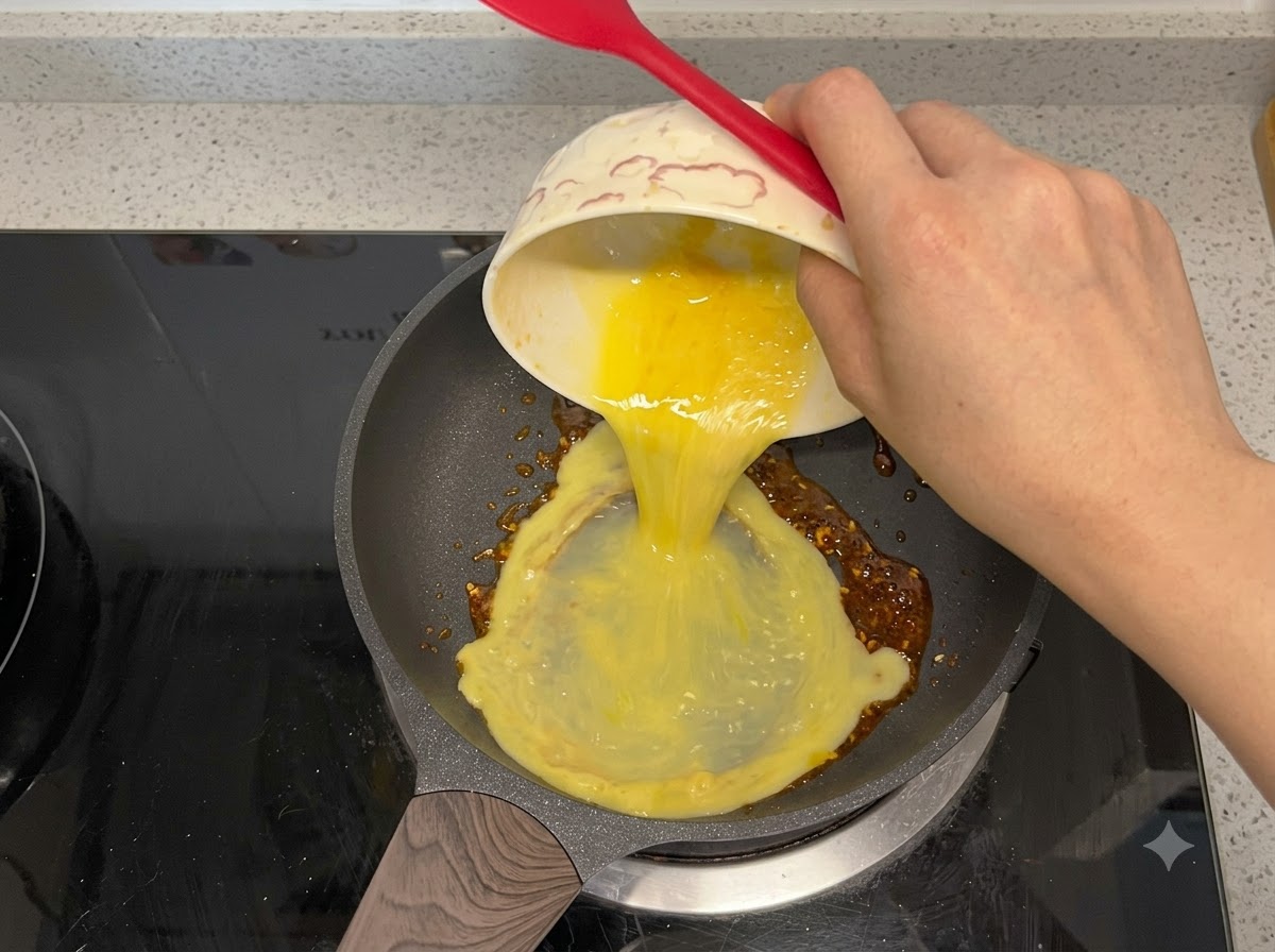 Verquirlte Eier werden in eine Bratpfanne mit Chiliöl gegossen.