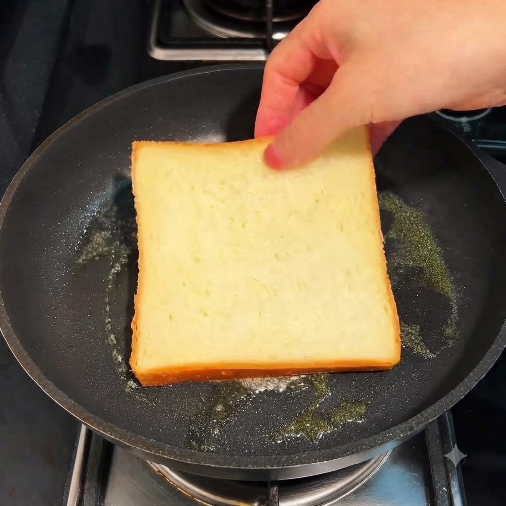 Eine Scheibe Weißbrot wird in einer Bratpfanne mit Butter über niedriger Flamme getoastet.