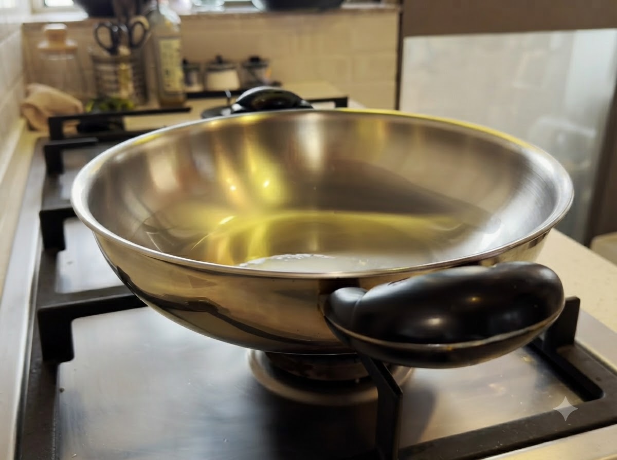 Kleine Hähnchenstücke werden in einem erhitzten Metall-Wok mit Olivenöl umgerührt.