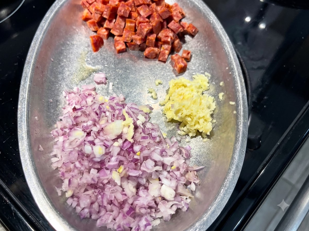 Ein Metallteller mit getrennten Haufen gewürfelter roter Zwiebel, gehacktem Knoblauch und gewürfelter spanischer Chorizo.