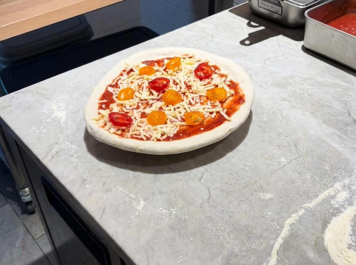 Eine vollständig belegte Pizza liegt auf einem Metalschieber auf einer Marmorarbeitsplatte.