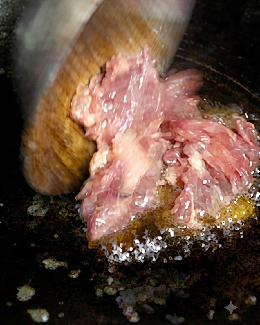 Gehacktes Fleisch wird mit einem Holzspatel in heißes Öl in einer Pfanne gegeben.