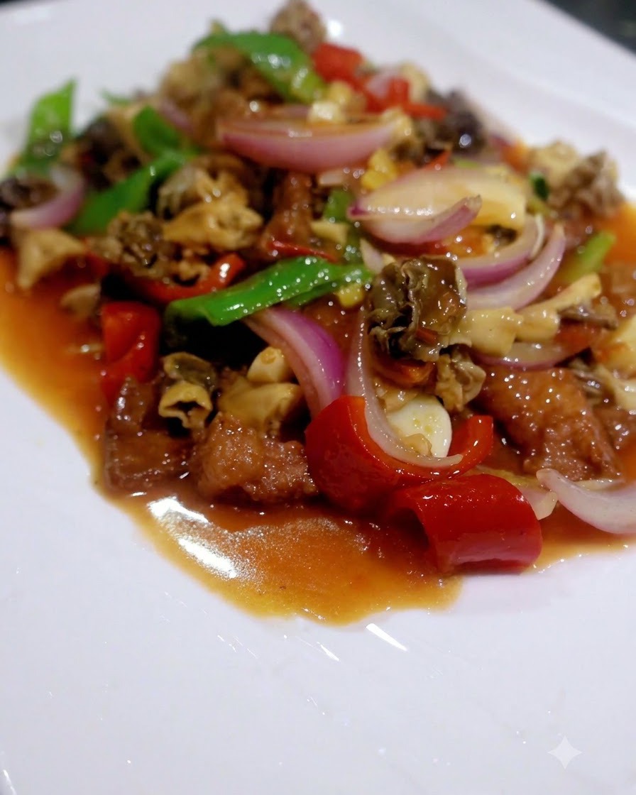 Ein fertiges Pfannengericht aus gemischten Pilzen, Paprika, Pak Choi und Fleisch, serviert auf einem weißen Teller.