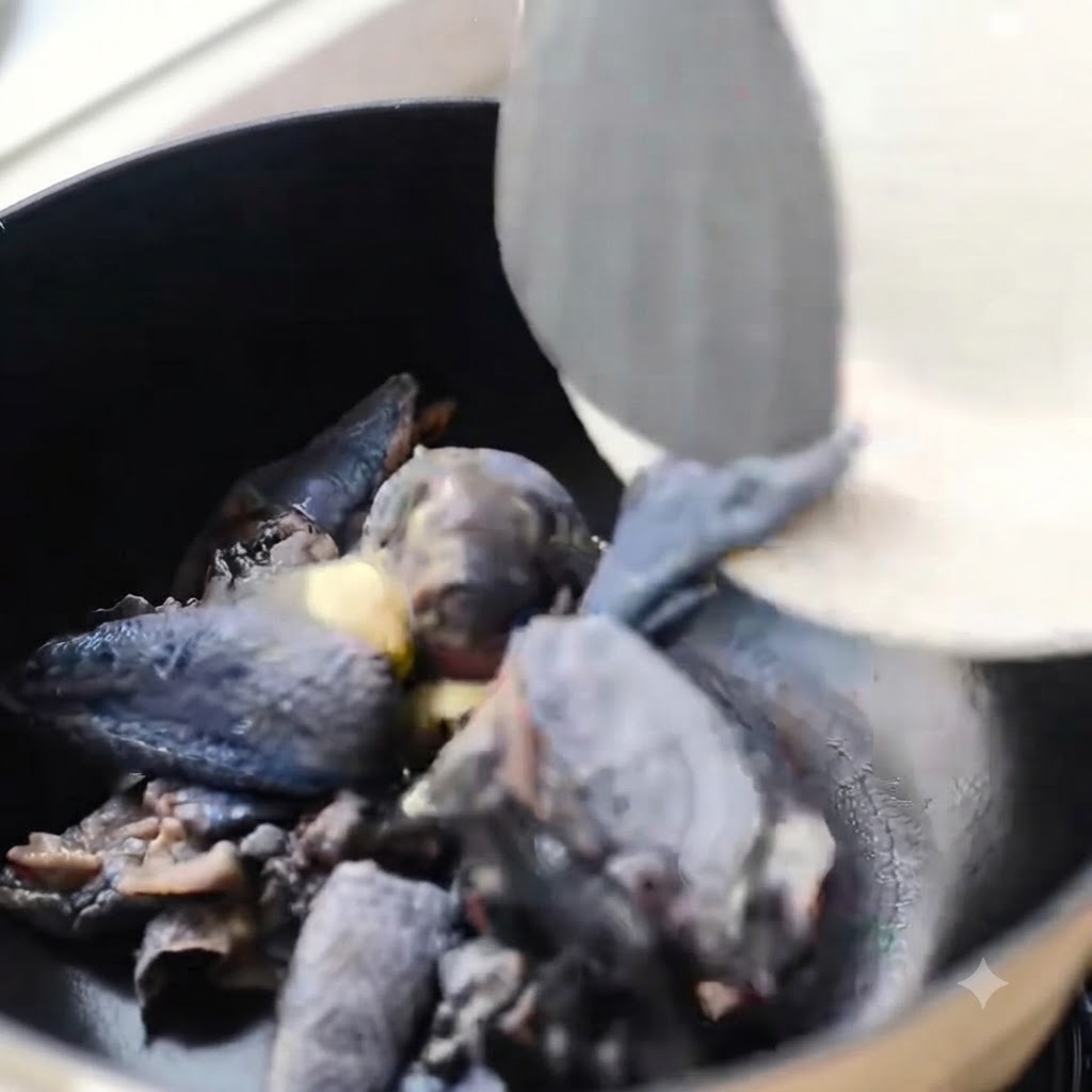 Schwarzschäbige Hühnerstücke, die in einem schwarzen Topf mit Ingwer angebraten werden.