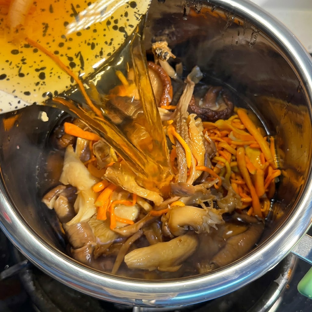 Pilz-Einweichwasser wird in den mit Zutaten gefüllten Topf gegossen.