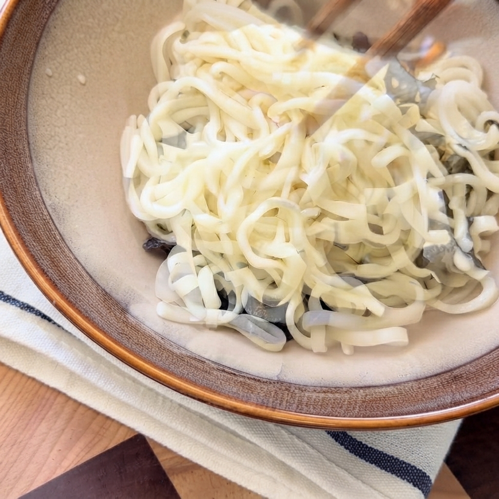 Heiße Pilzsuppe wird von oben über die Nudeln in der Servierschüssel gegossen.