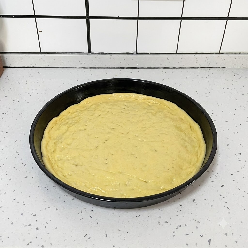 Ein schwarzes Küchenwerkzeug wird verwendet, um kleine Löcher gleichmäßig über einen flachen runden Pizzateig in einer schwarzen Pfanne zu stechen.