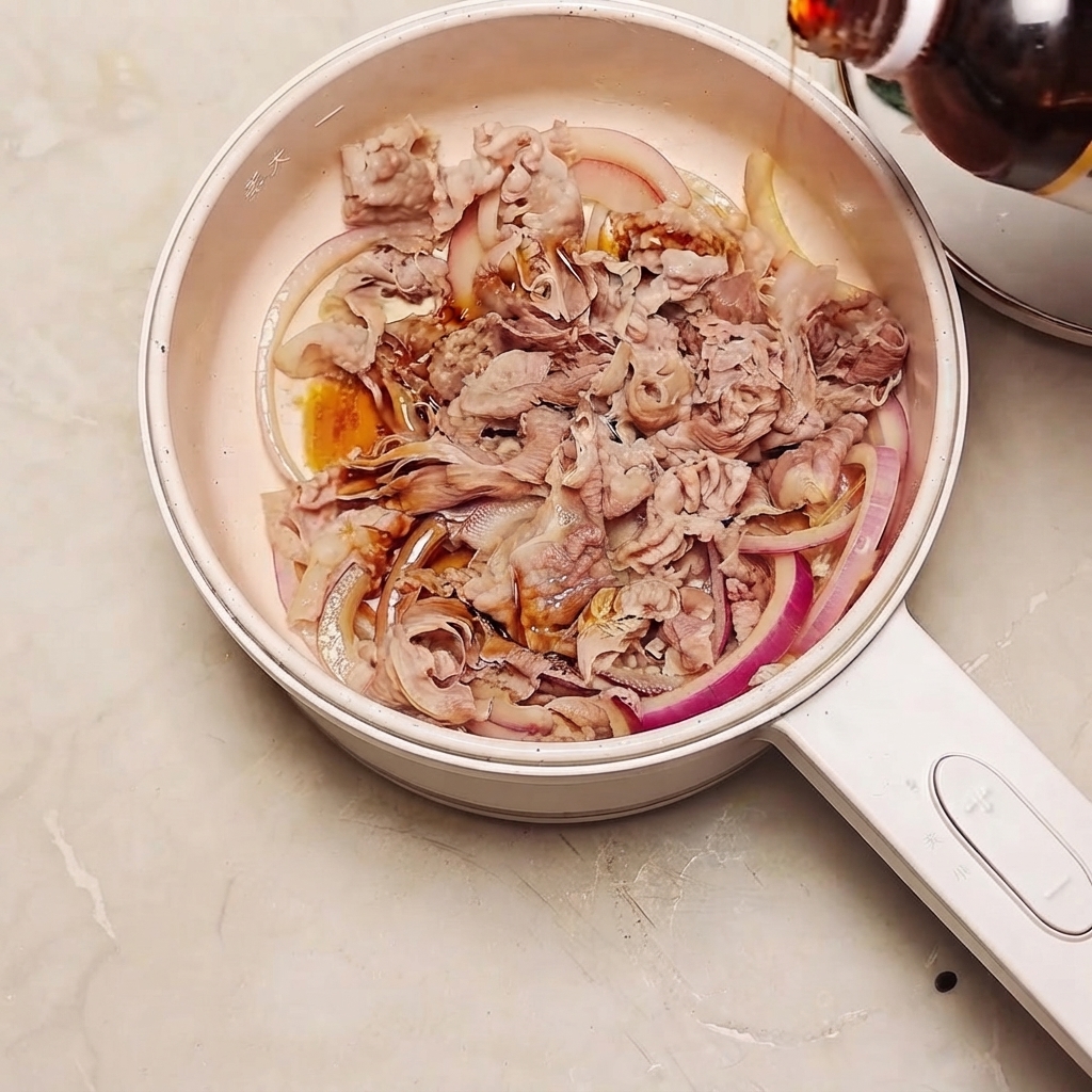 Sukiyaki-Sauce wird aus einer Flasche in eine Pfanne mit Rindfleisch und roten Zwiebeln gegossen.