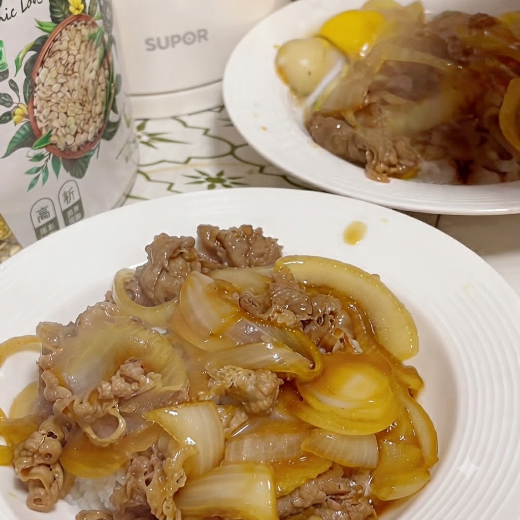 Ein fertiger Teller mit Rindfleisch und Zwiebeln auf Reis, wobei ein aufgeschlagenes rohes Eigelb in einer kleinen Vertiefung in der Mitte sitzt.