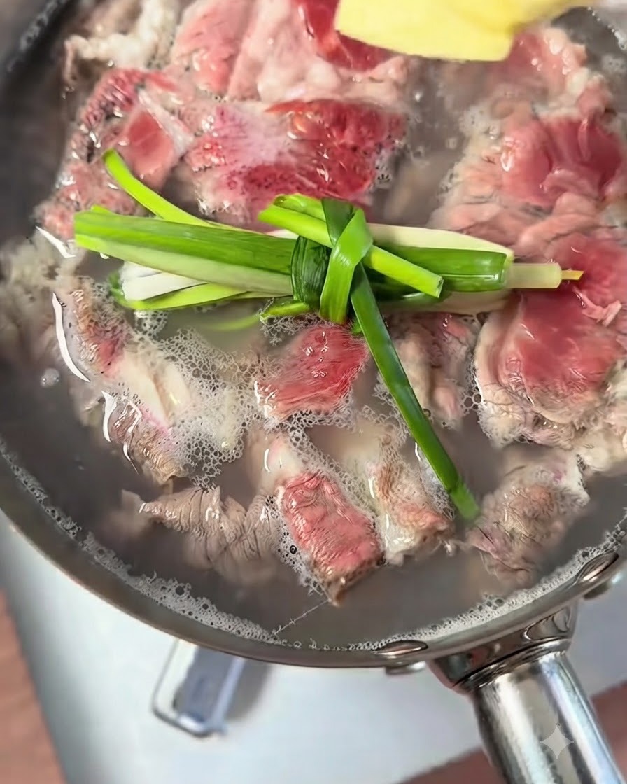 Frühlingszwiebelknoten und Ingwerstücke schwimmen in einem Topf mit kochendem Rindfleisch.