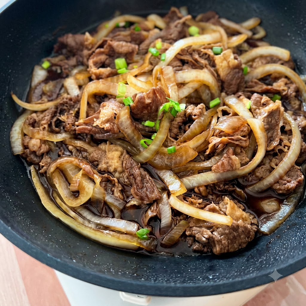 Eine Pfanne voller gekochtem Rindfleisch und Zwiebeln, garniert mit Frühlingszwiebelstücken und weißem Sesam.
