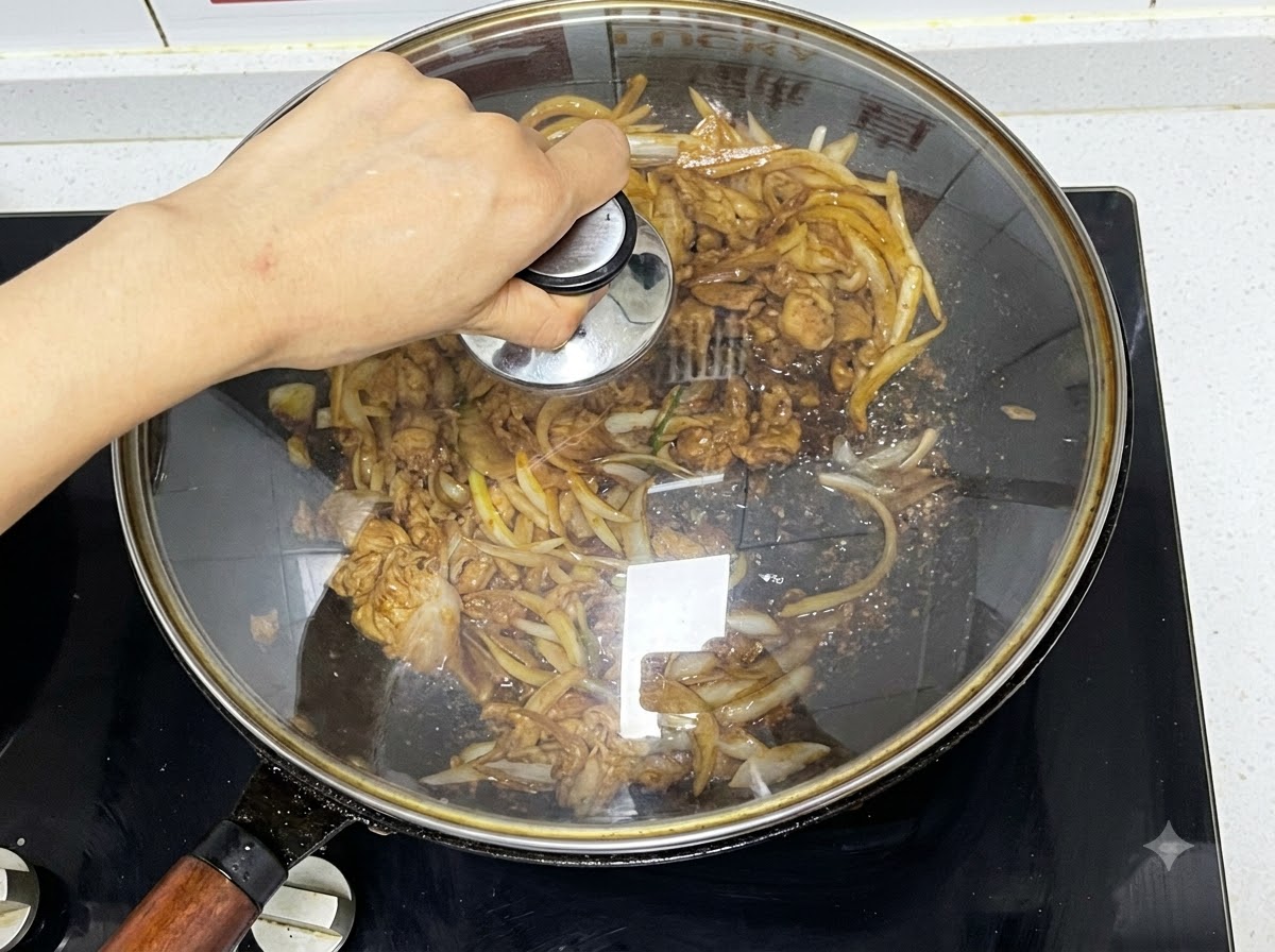 Ein Glasdeckel wird auf einen Wok gelegt, der köchelndes Rindfleisch und Zwiebeln enthält.