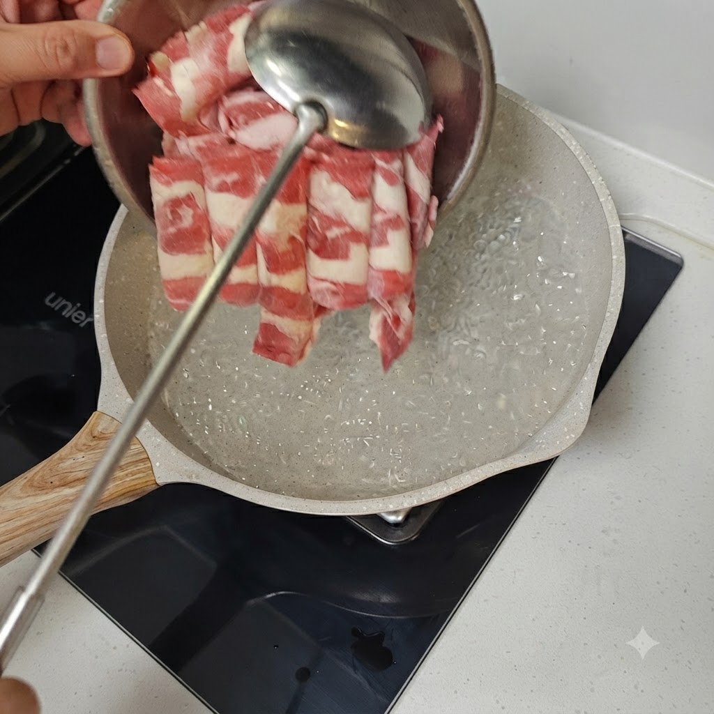 Dünn geschnittenes Rindfleisch wird mit einer Metallkelle in eine Pfanne mit kochendem Wasser gegeben.