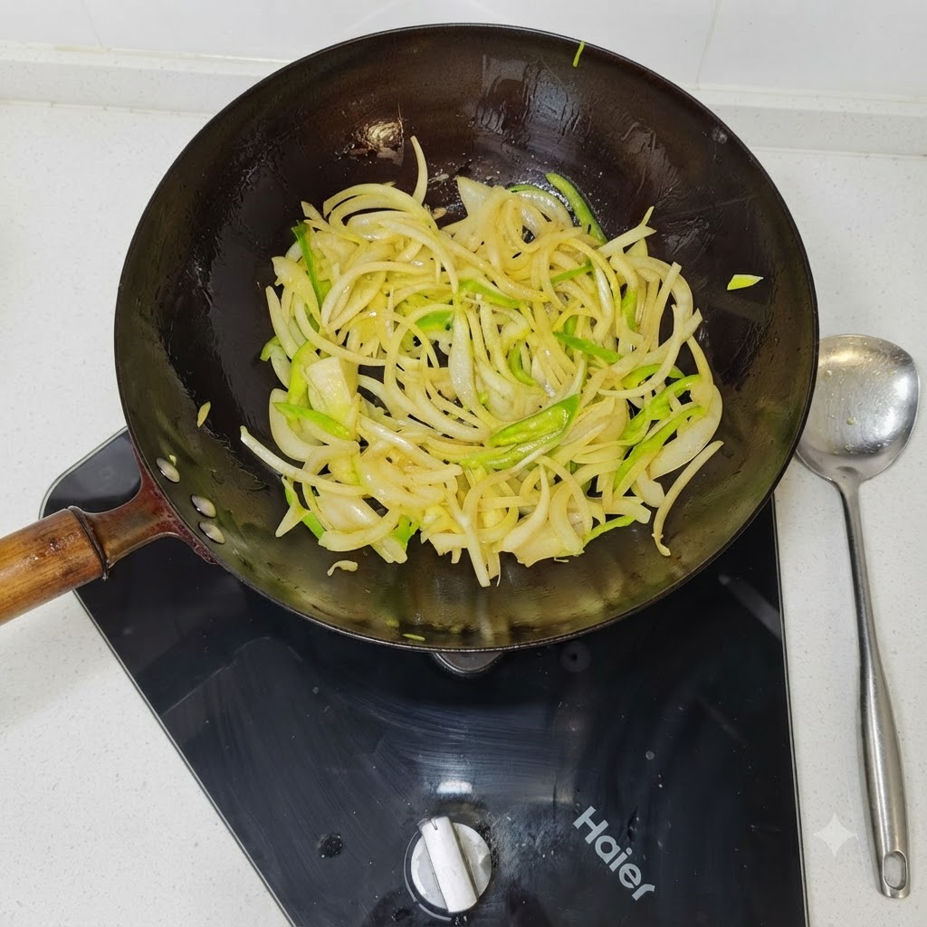 Zwiebel- und grüne Paprikastreifen werden in einem heißen schwarzen Wok angebraten.