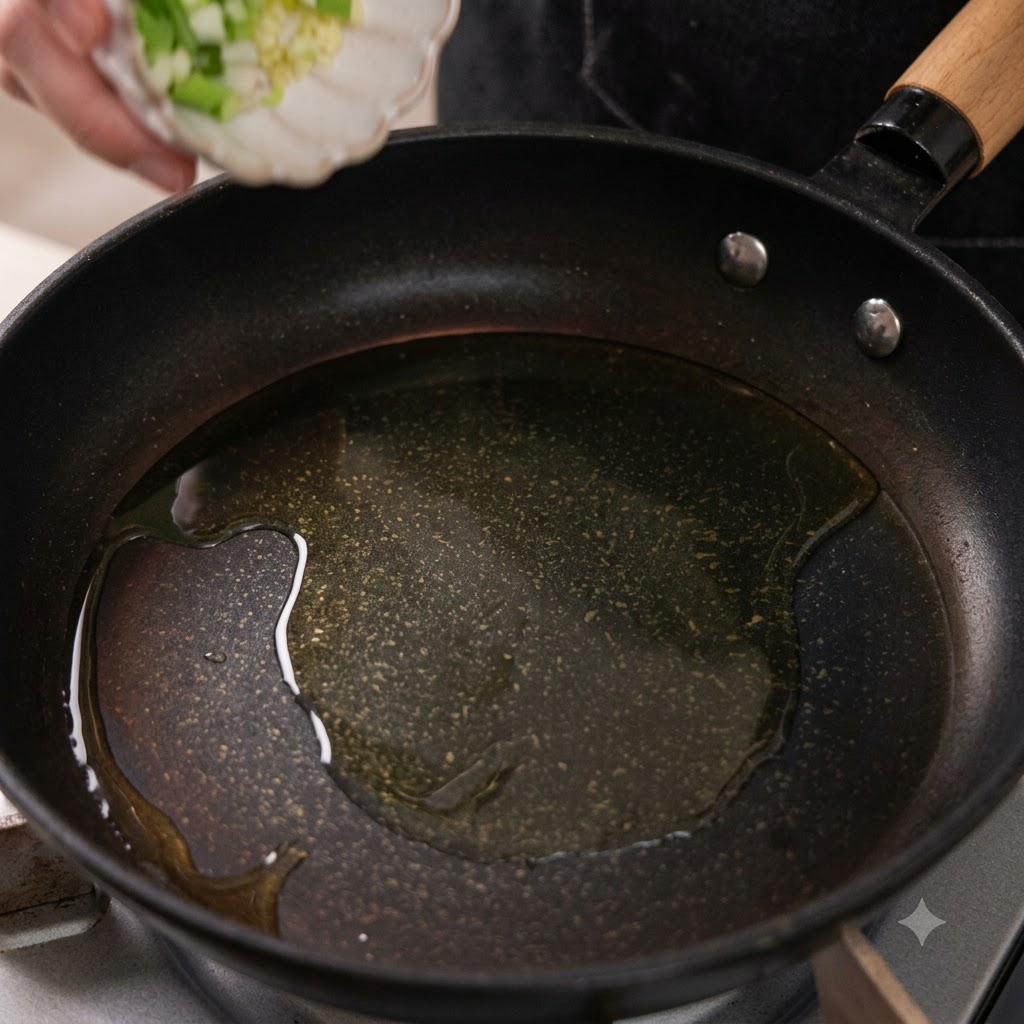 Gehackter Knoblauch und gehackte Frühlingszwiebel-Weiße fallen in eine Bratpfanne mit erhitztem Öl.
