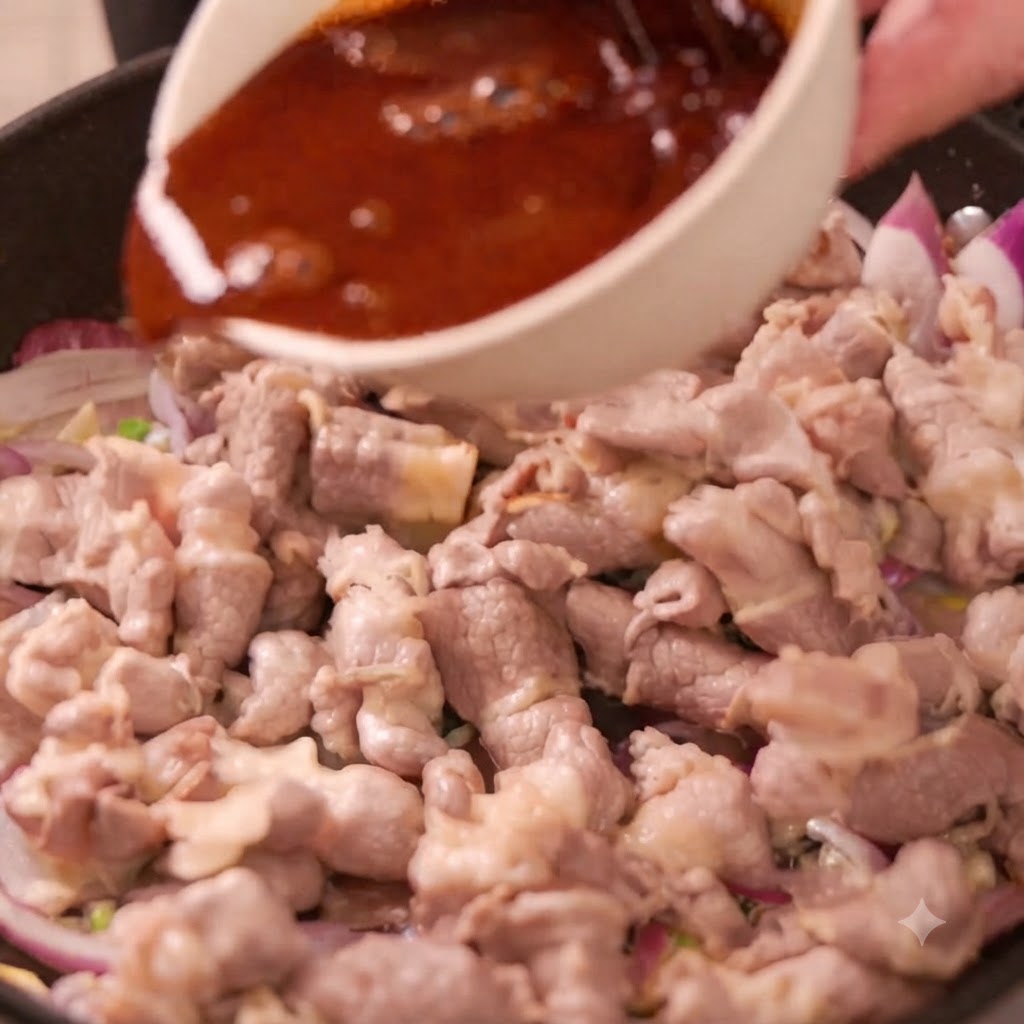 Eine Schüssel dunkle Sauce wird in eine Pfanne mit Rindfleischröllchen und in Scheiben geschnittenen roten Zwiebeln gegossen.