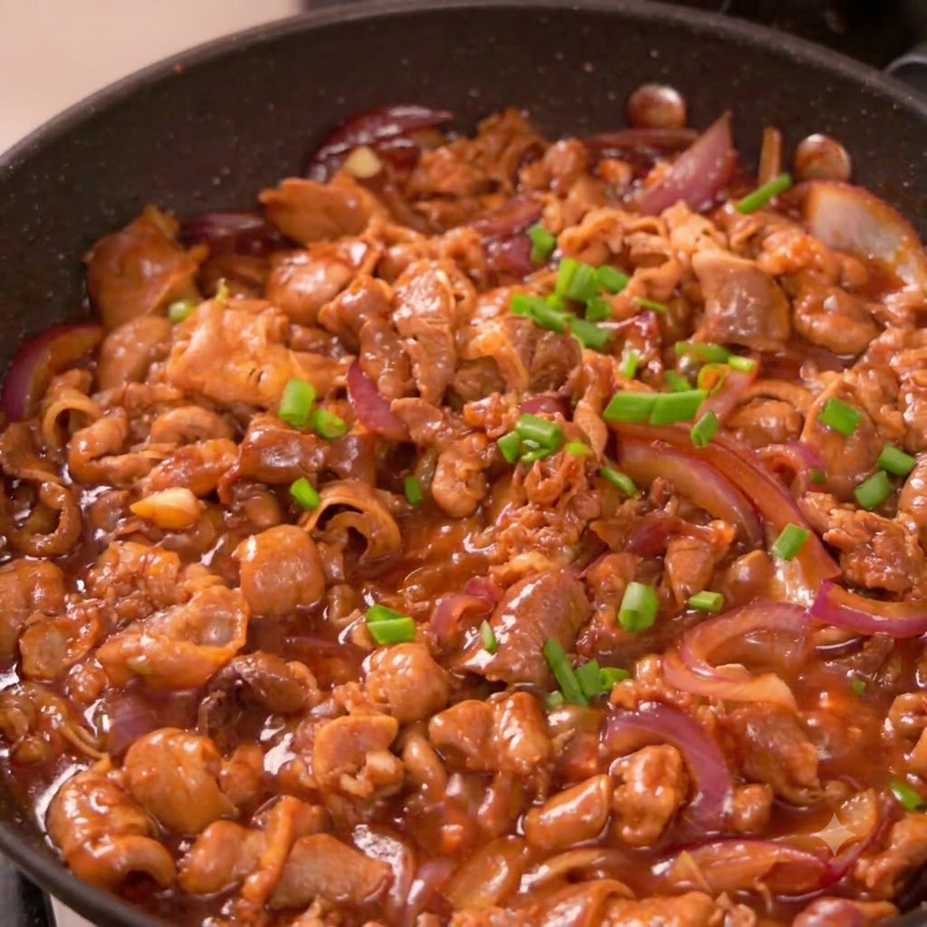 In Scheiben geschnittene Frühlingszwiebelstücke sind über gekochtem Rindfleisch und roten Zwiebeln in einer Bratpfanne verstreut.