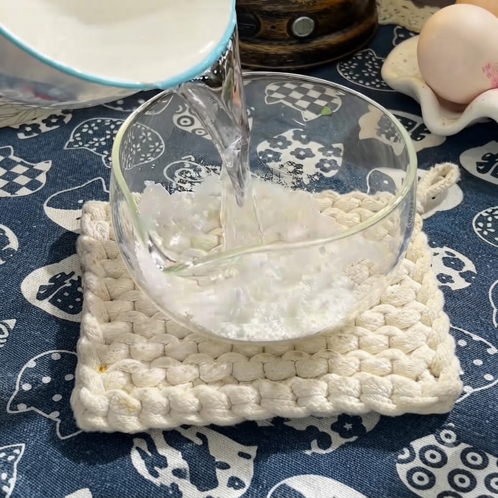 Wasser wird in eine Schüssel mit Speisestärke gegossen, um eine flüssige Basis zu bilden.