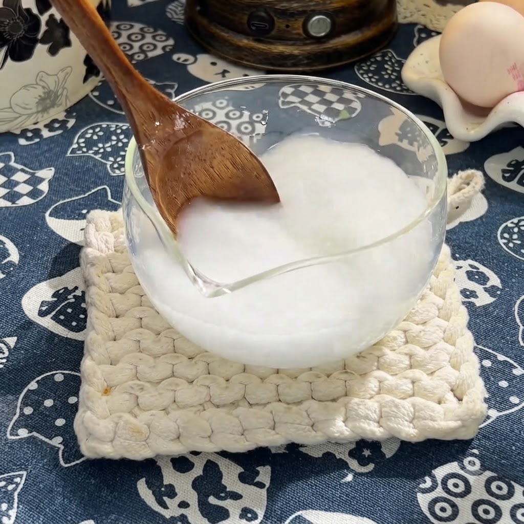 Ein Holzlöffel rührt Sojasauce, Austernsauce und Honig in die Stärkemischung ein.