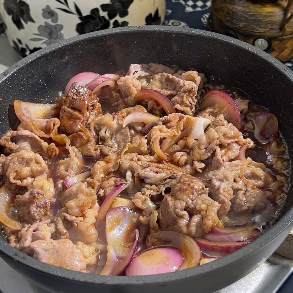 Teriyaki-Sauce wird aus einem Behälter in eine Bratpfanne mit angebratenem Rindfleisch und roten Zwiebeln gegossen.