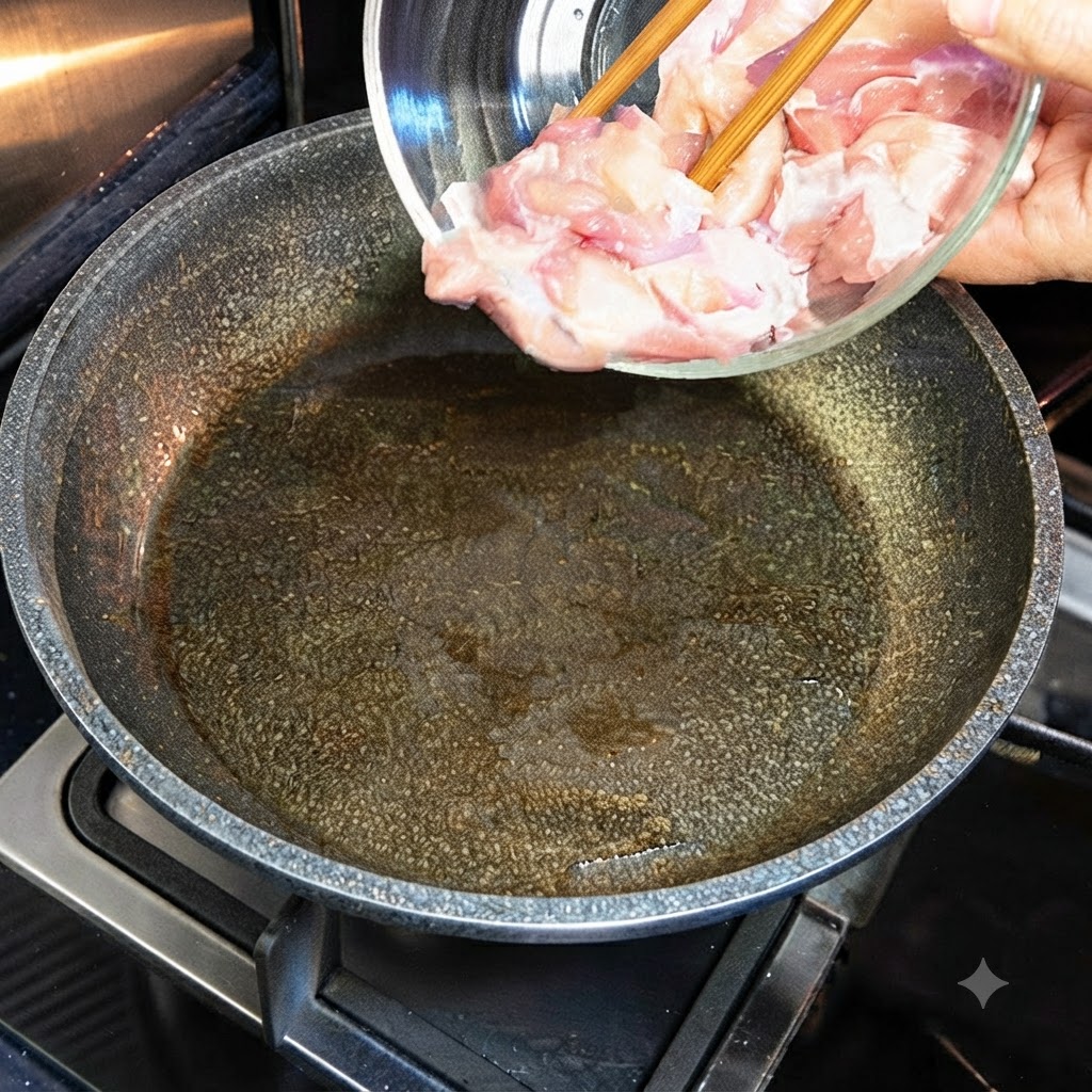 Rohe Hähnchenstücke werden aus einer Glasschüssel in eine heiße, geölte Pfanne gegeben.