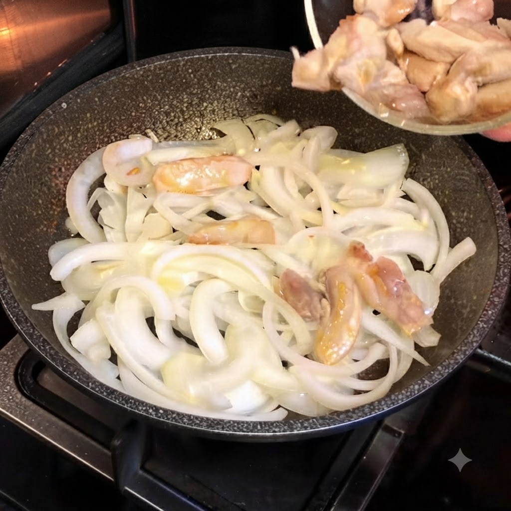 Teilweise gegarte Hähnchenstücke werden aus einer kleinen Glasschüssel in eine heiße Pfanne mit weißen Zwiebeln gefüllt.