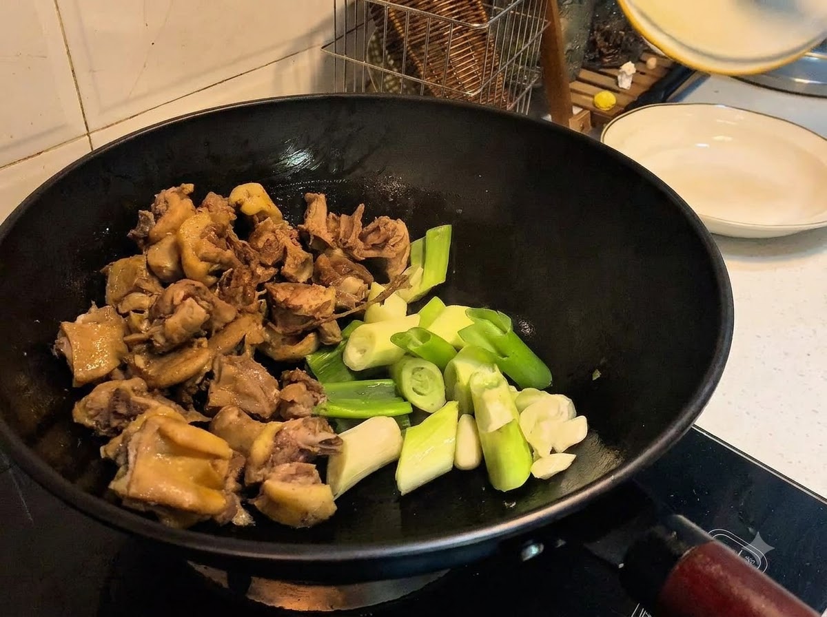 Frühlingszwiebeln, Knoblauch, Ingwer und Gewürze werden zusammen mit der Ente in den Wok gegeben.