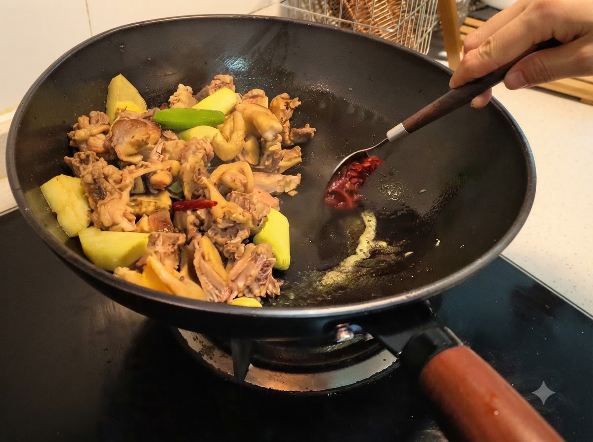 Bohnenpaste wird in den Wok geschöpft und mit einem Löffel mit den Zutaten vermischt.