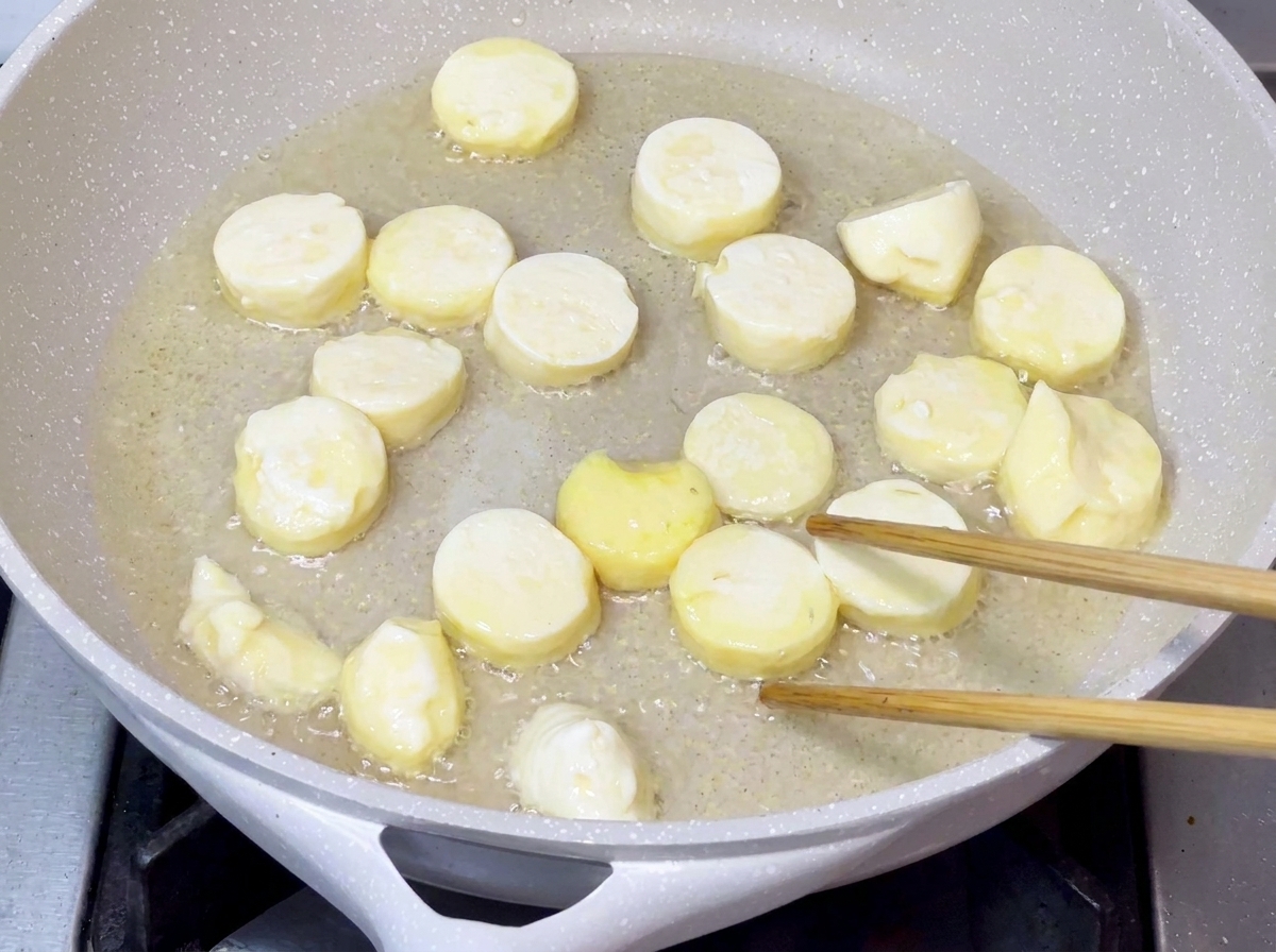 Tofustücke, die in heißem Öl in einer Pfanne gebraten werden, bis ihre Oberfläche goldbraun und knusprig ist.