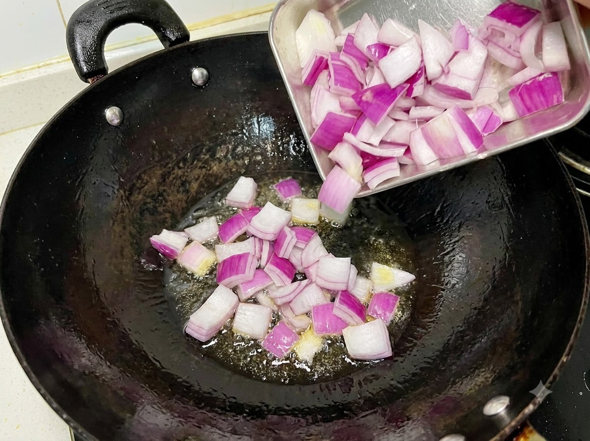 Gewürfelte rote Zwiebeln brutzeln und werden in einem geölten schwarzen Wok angebraten.