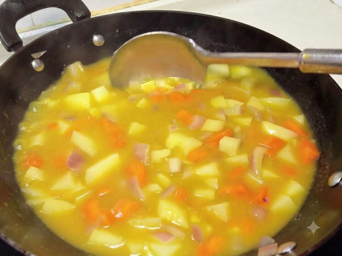 Eine Schöpfkelle rührt eine dicke, reichhaltige gelbe Currysauce mit Kartoffeln und Karotten in einem Wok um.