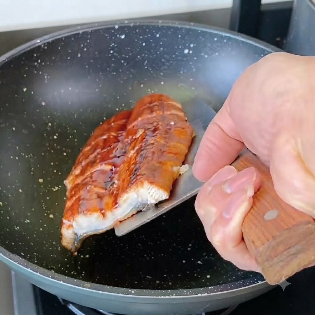 Geschnittene Aalteile werden in einer Pfanne angebraten.