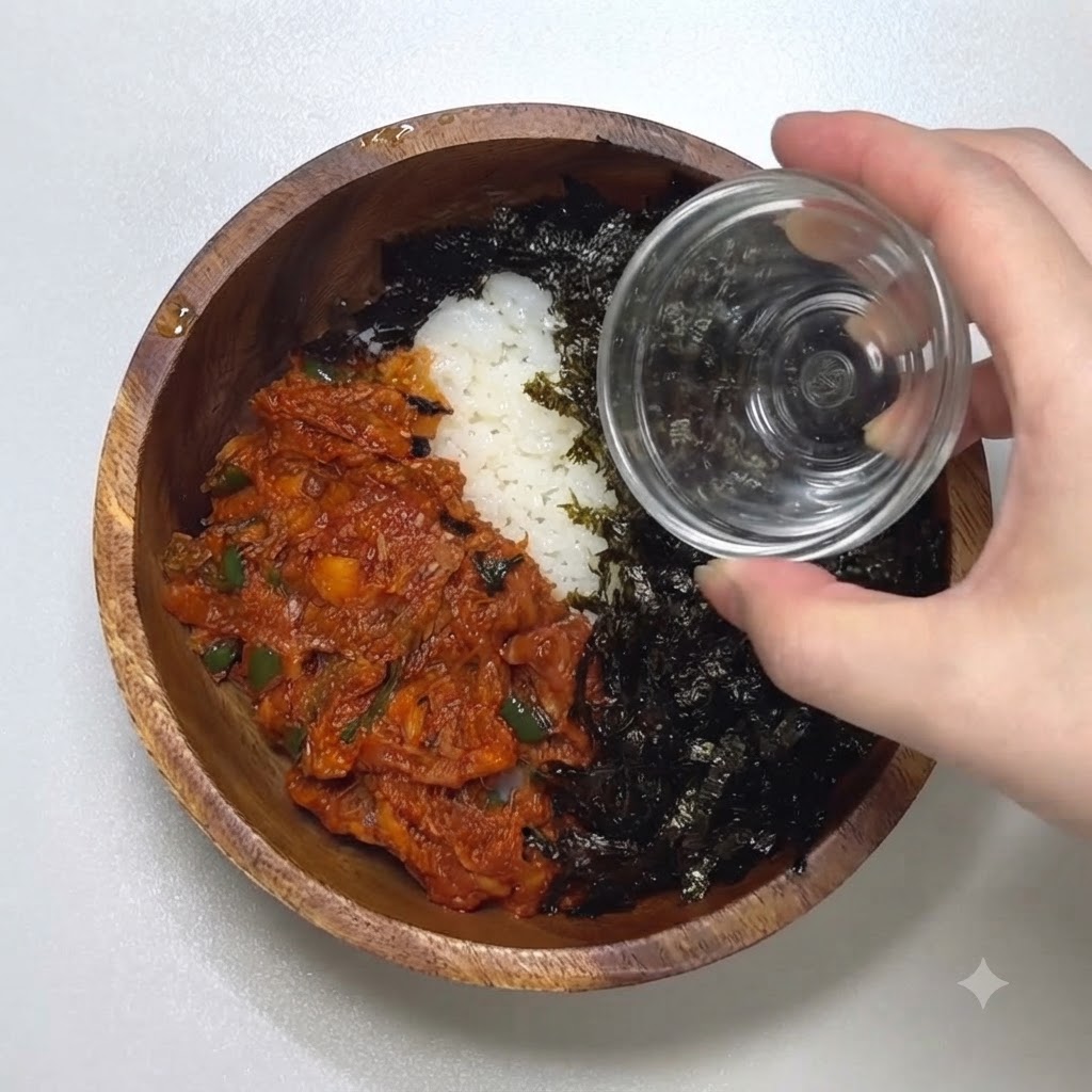 Nahaufnahme einer Hand, die geröstete Sesamsamen aus einem kleinen Glasgefäß über eine Schüssel mit Algen und scharfem Thunfisch streut.