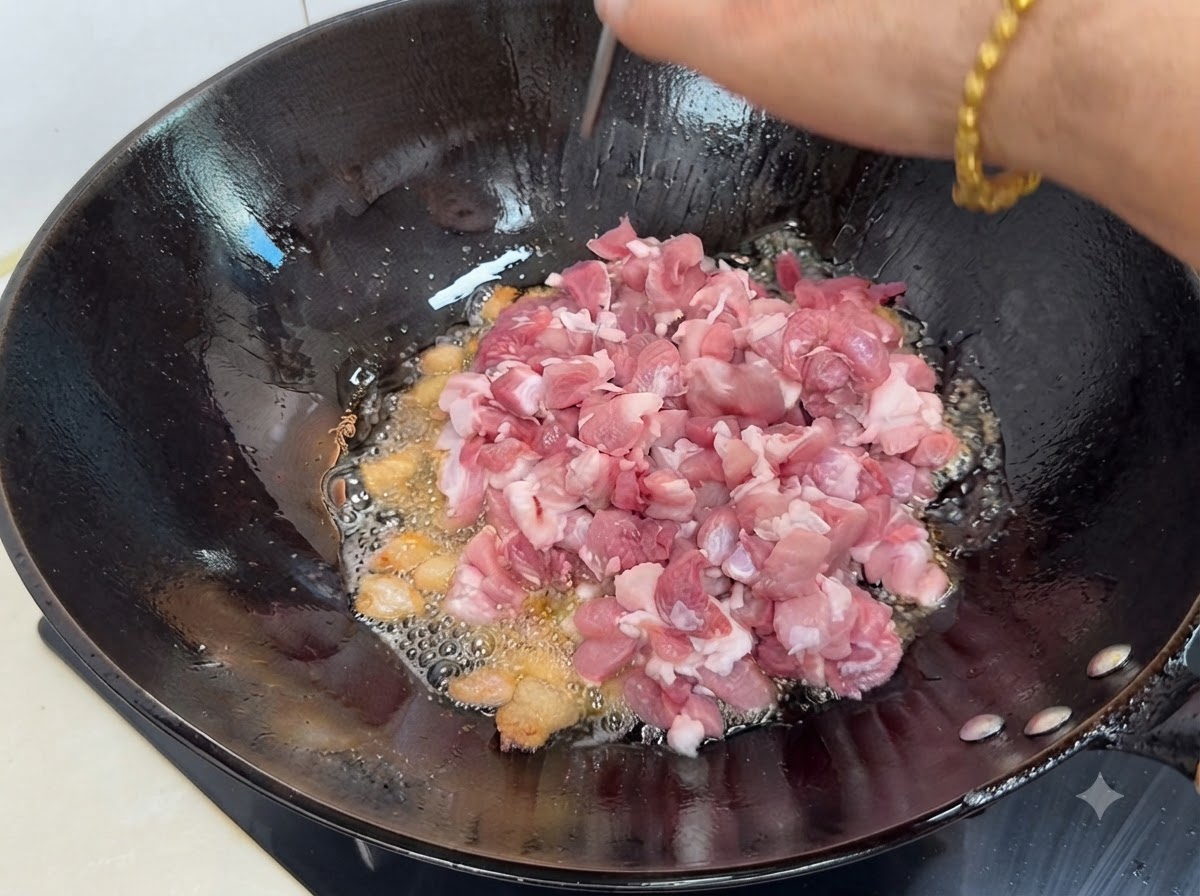Frische gewürfelte magere Schweinefleischstücke werden in den heißen Wok gegeben.