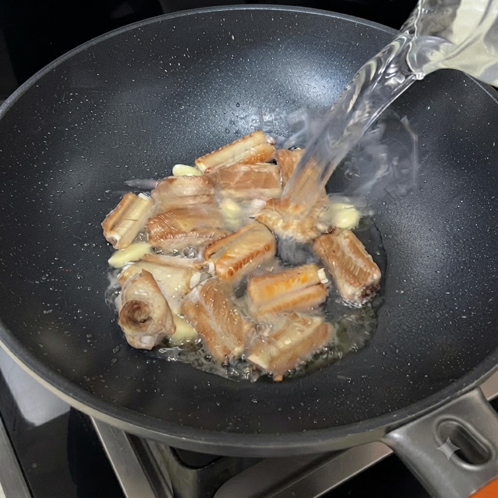 Wasser strömt aus einer Schüssel in die brutzelnde Pfanne mit Rippchen und Knoblauch.