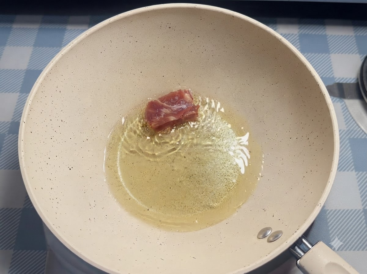 Ein einzelnes Stück Schweinerippchen wird mit Stäbchen in das heiße Öl in einer weißen Bratpfanne gelegt.