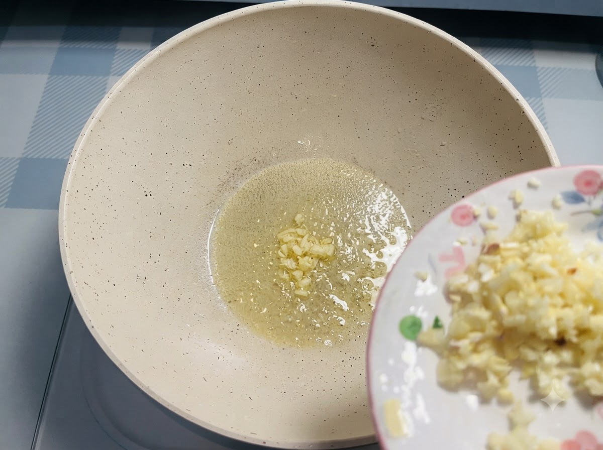 Gehackter Knoblauch rutscht von einem kleinen Teller in geschmolzene Butter in einer Pfanne.