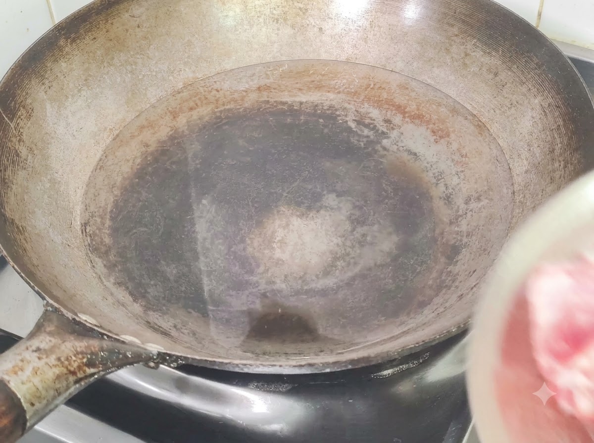 Schweinerippchen werden in einen mit kaltem Wasser, Ingwer und Kochwein gefüllten Wok zum Blanchieren gegeben.