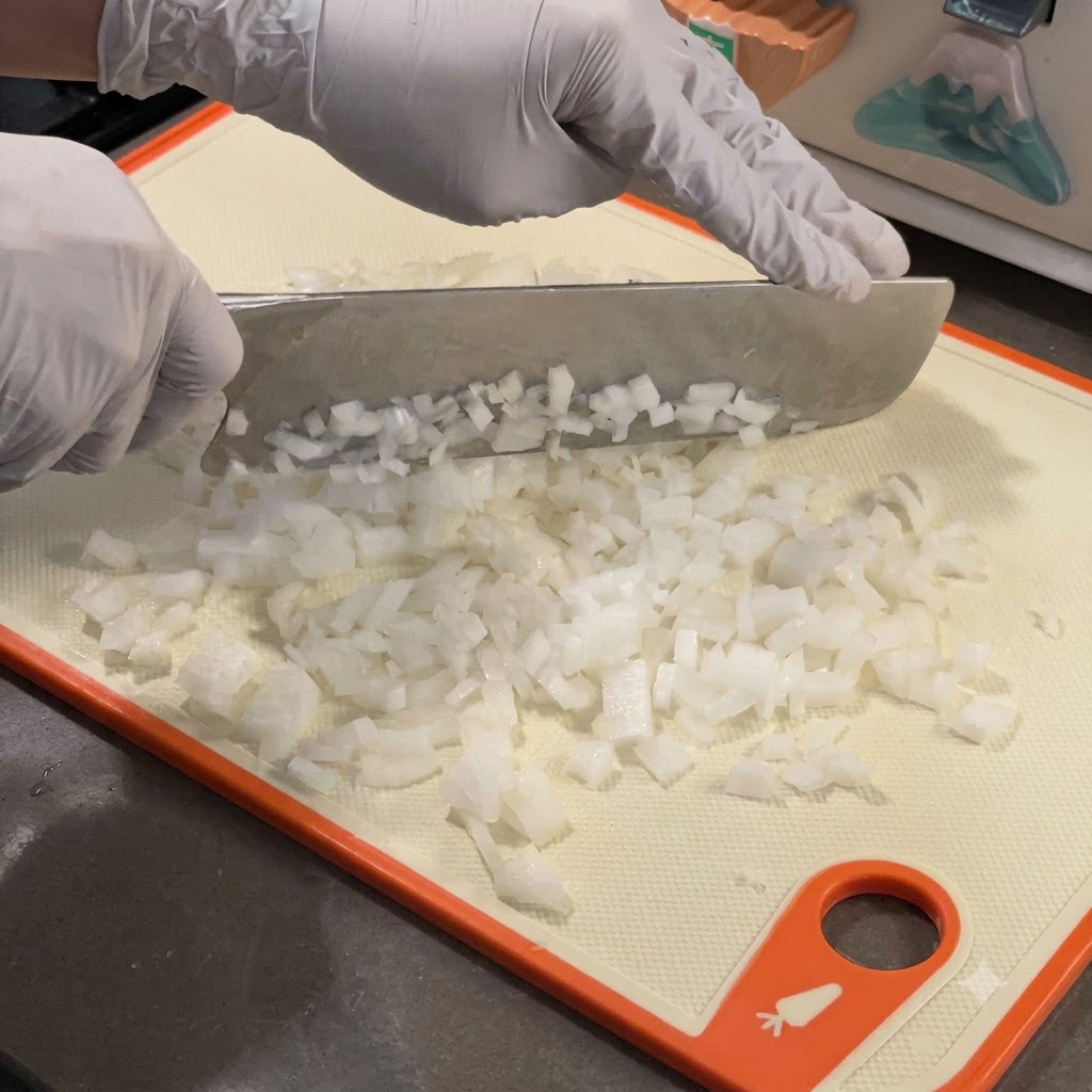 Fein gewürfelte weiße Zwiebeln garen in einer heißen Gusseisenpfanne.