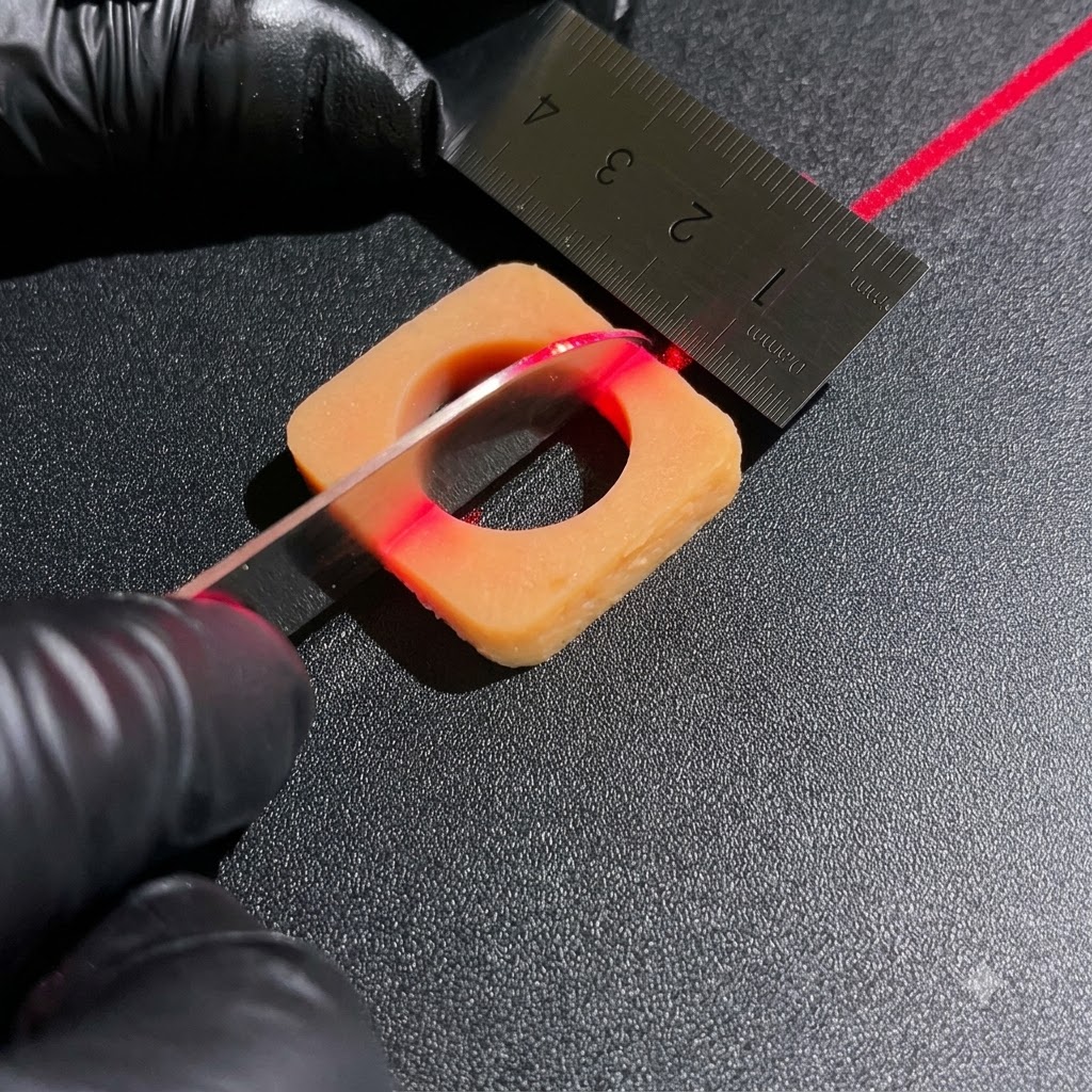 Bewehrte Hände benutzen ein scharfes Messer und ein Metalllineal, um quadratische Zutatenblöcke unter einer roten Laserausrichtungslinie zu schneiden.