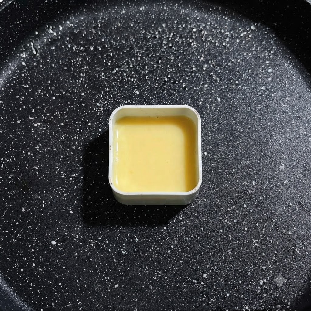 Eine quadratische Metallform, gefüllt mit gelber Eierflüssigkeit, steht in der Bratpfanne und ist bereit für die Zutatenplatzierung.