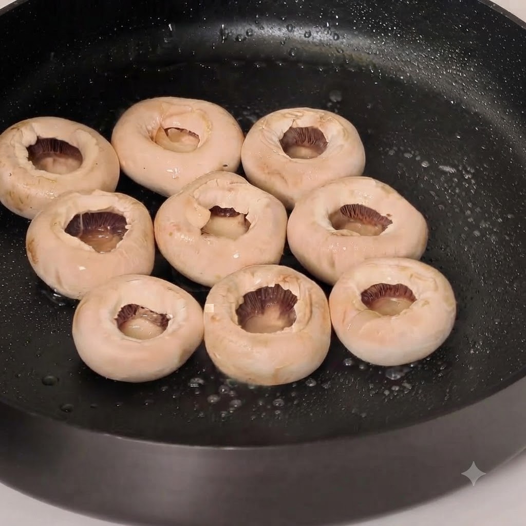 Ganze weiße Champignonköpfe braten in einer geölten Pfanne mit Pfefferwürzung.