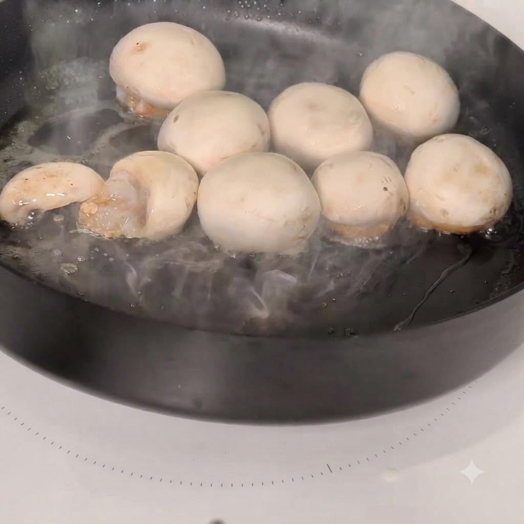 Mit Garnelen gefüllte Champignonköpfe garen in einer heißen Pfanne.