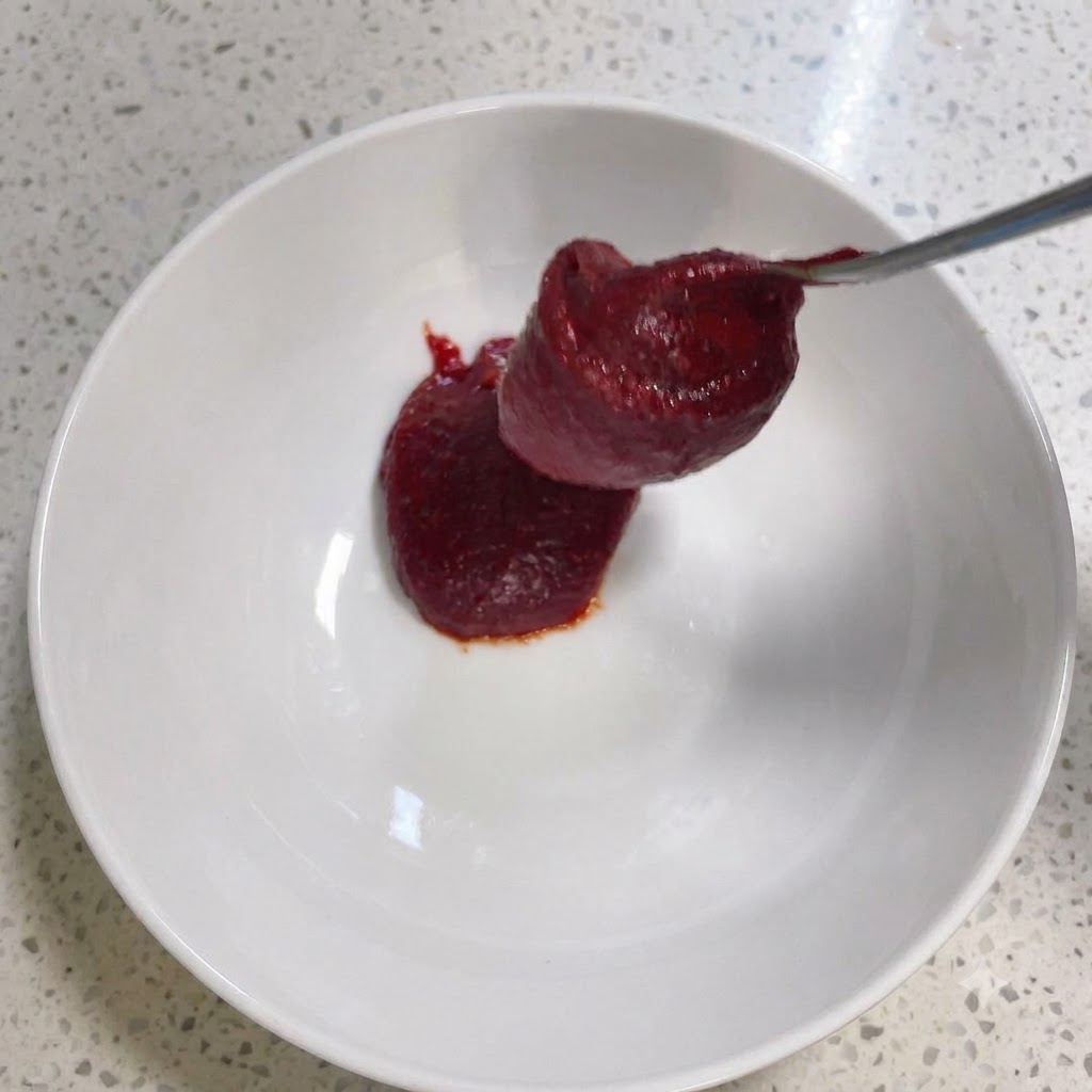 Koreanische Chilipaste und andere Gewürze werden in einer weißen Schüssel verrührt.